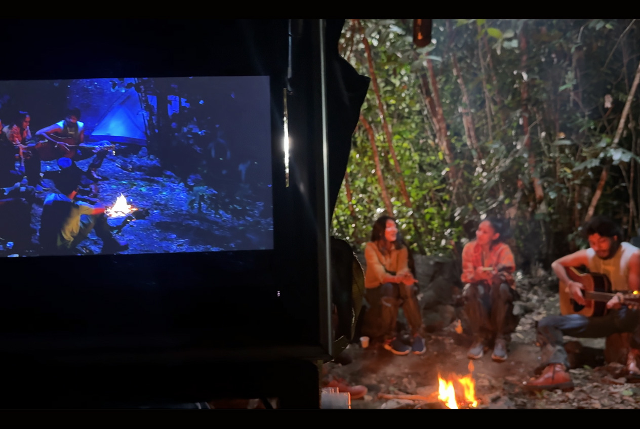 The actual filmed cinematic frame realising the same campfire concept on location